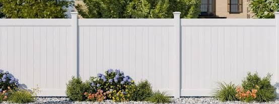 White fence with shrubs and flowers in front of a house