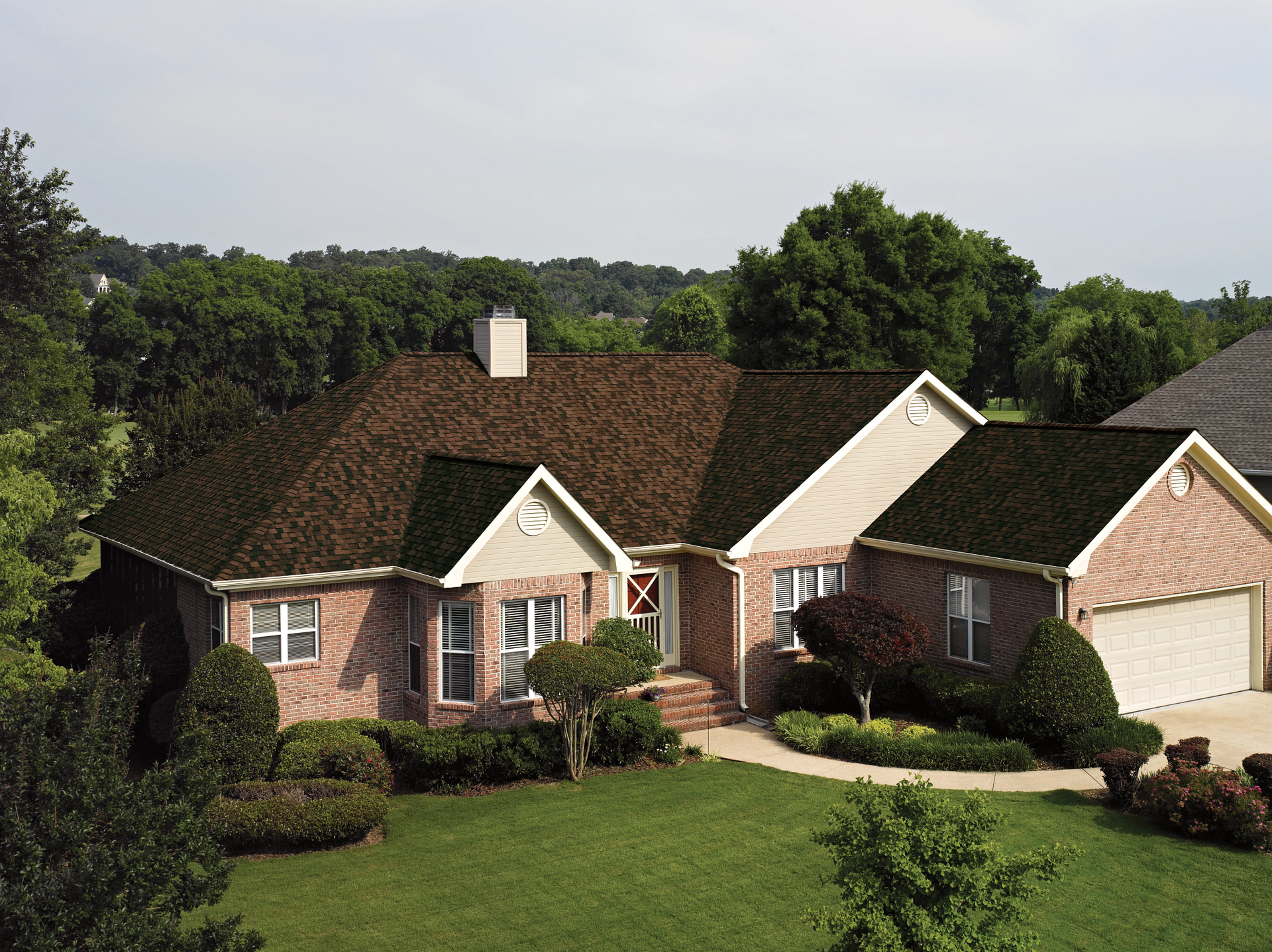 A brick house surrounded by lush, green trees.