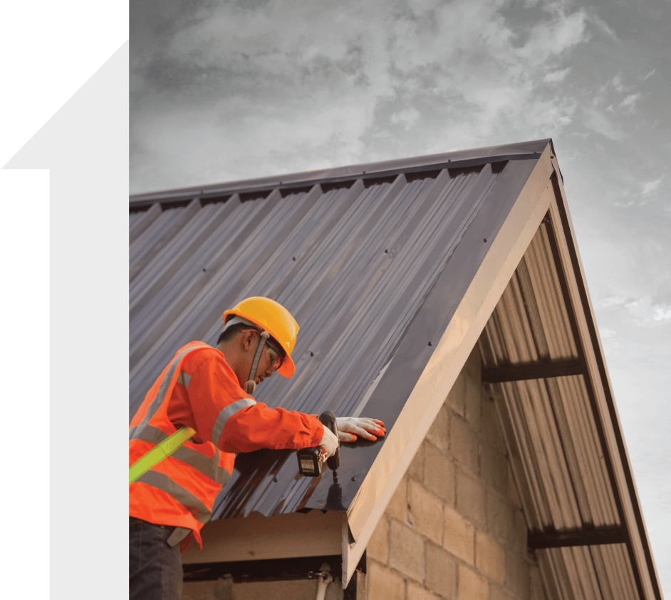 A man wearing a hard hat is working on a roof