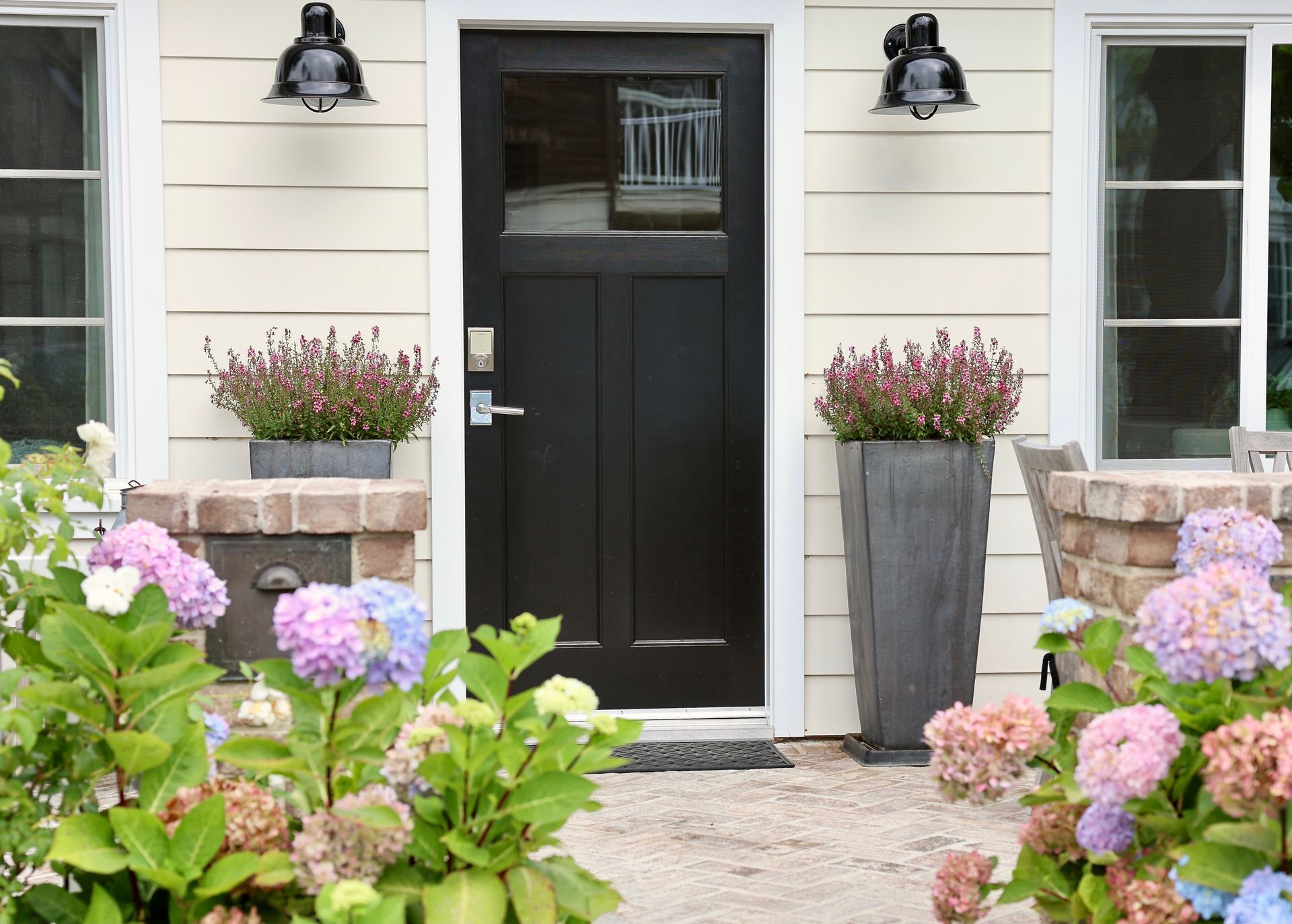 A house with a black door and flowers in front of it.
