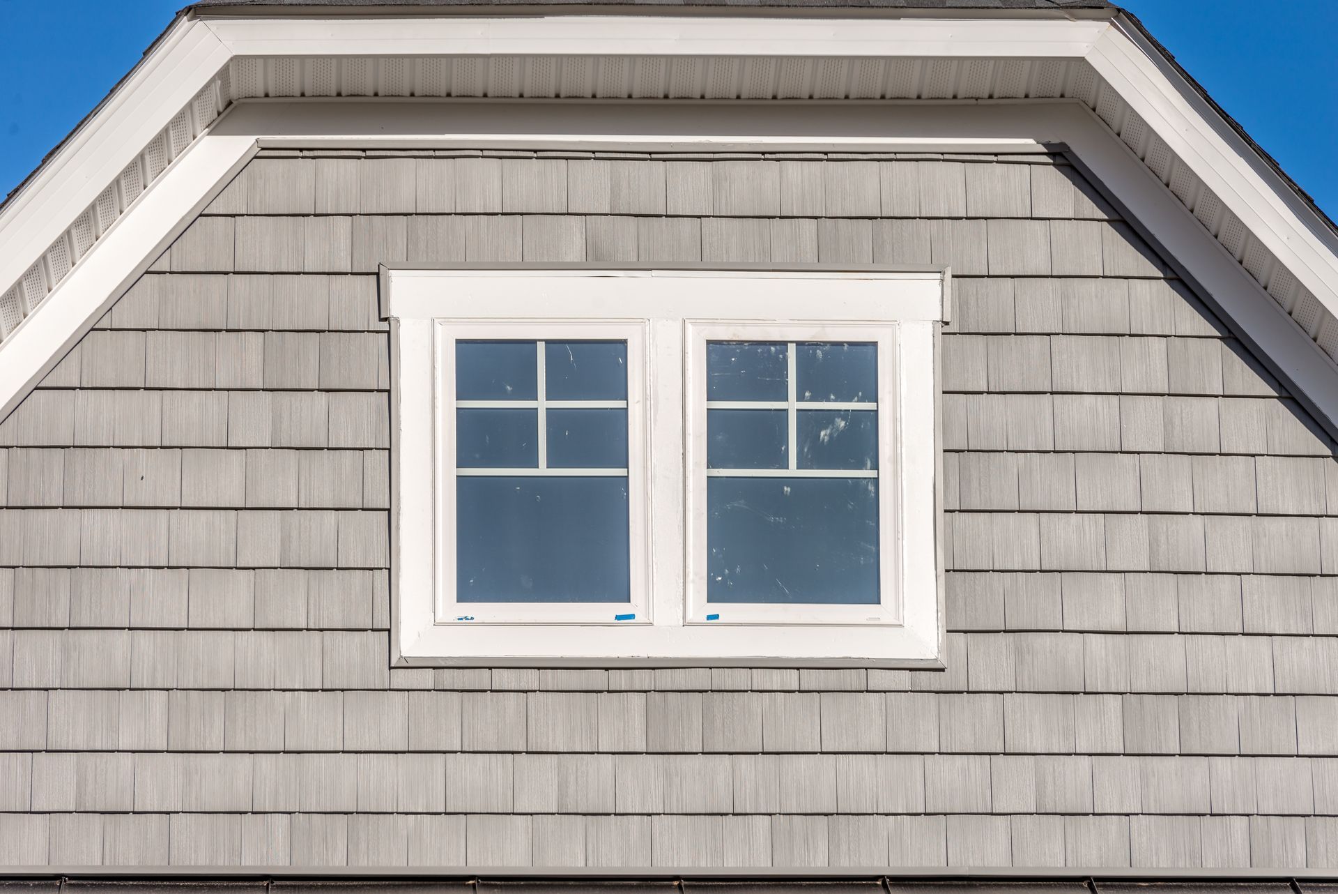 A white window is on the side of a house.
