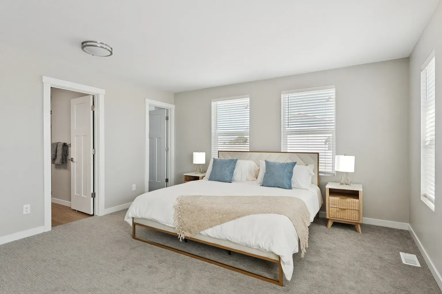 Bedroom in a modern apartment with a bed, two nightstands, and neutral decor.
