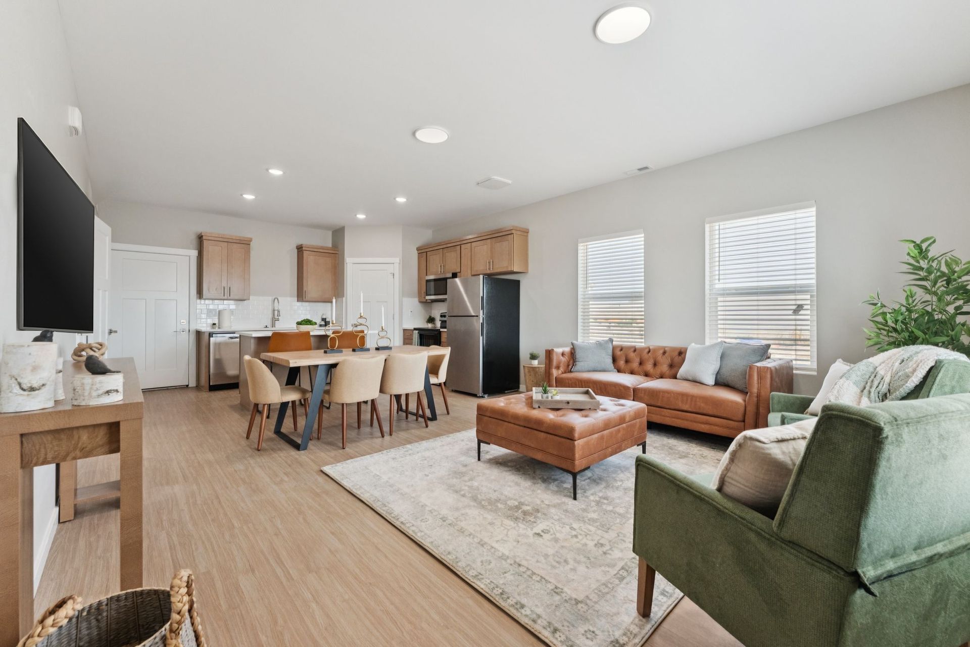 Open-concept living room and kitchen in a modern apartment with a dining table and seating.