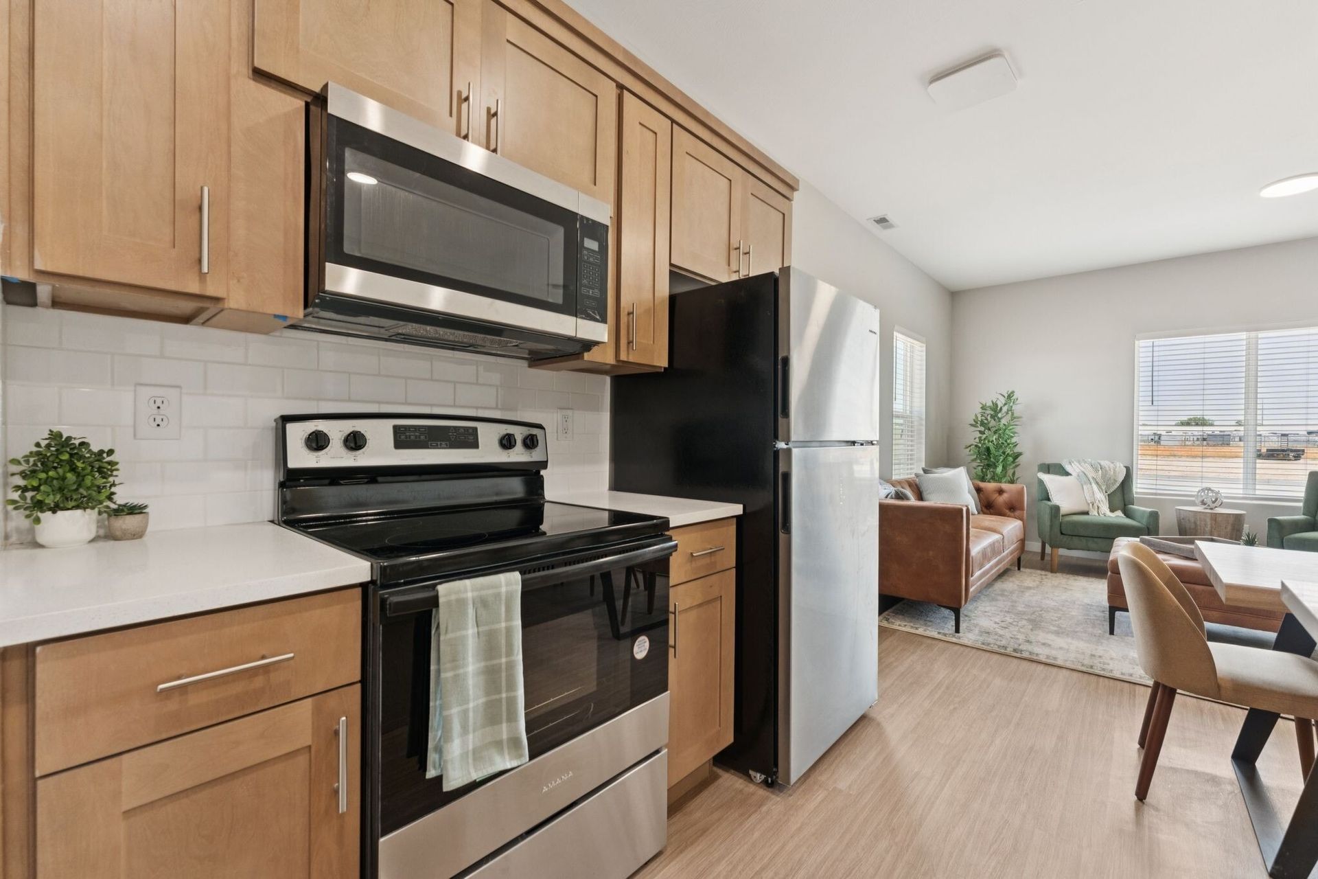 Kitchen with stainless steel stove, microwave, and refrigerator, plus light wooden cabinets.