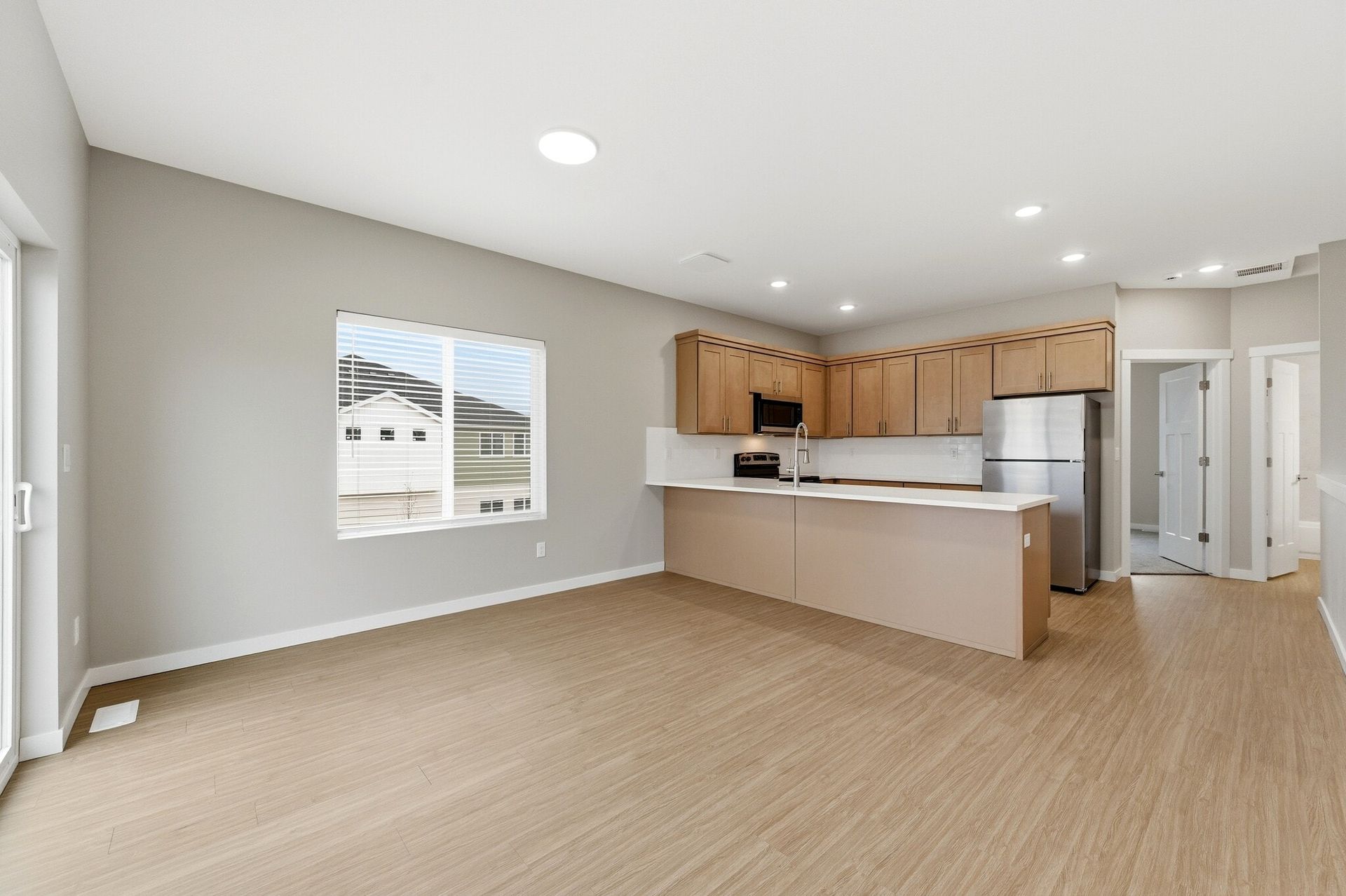 Open-concept kitchen with island, light wood cabinets and stainless steel appliances.