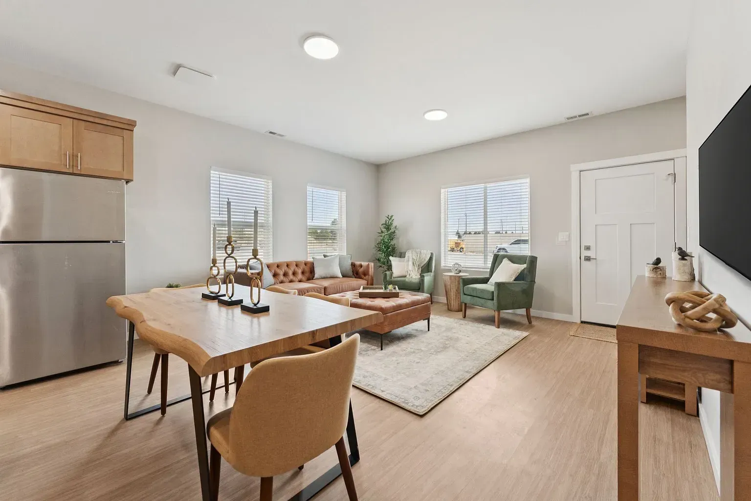 Open-concept living area with sofa, chairs, dining table, and a mounted TV.