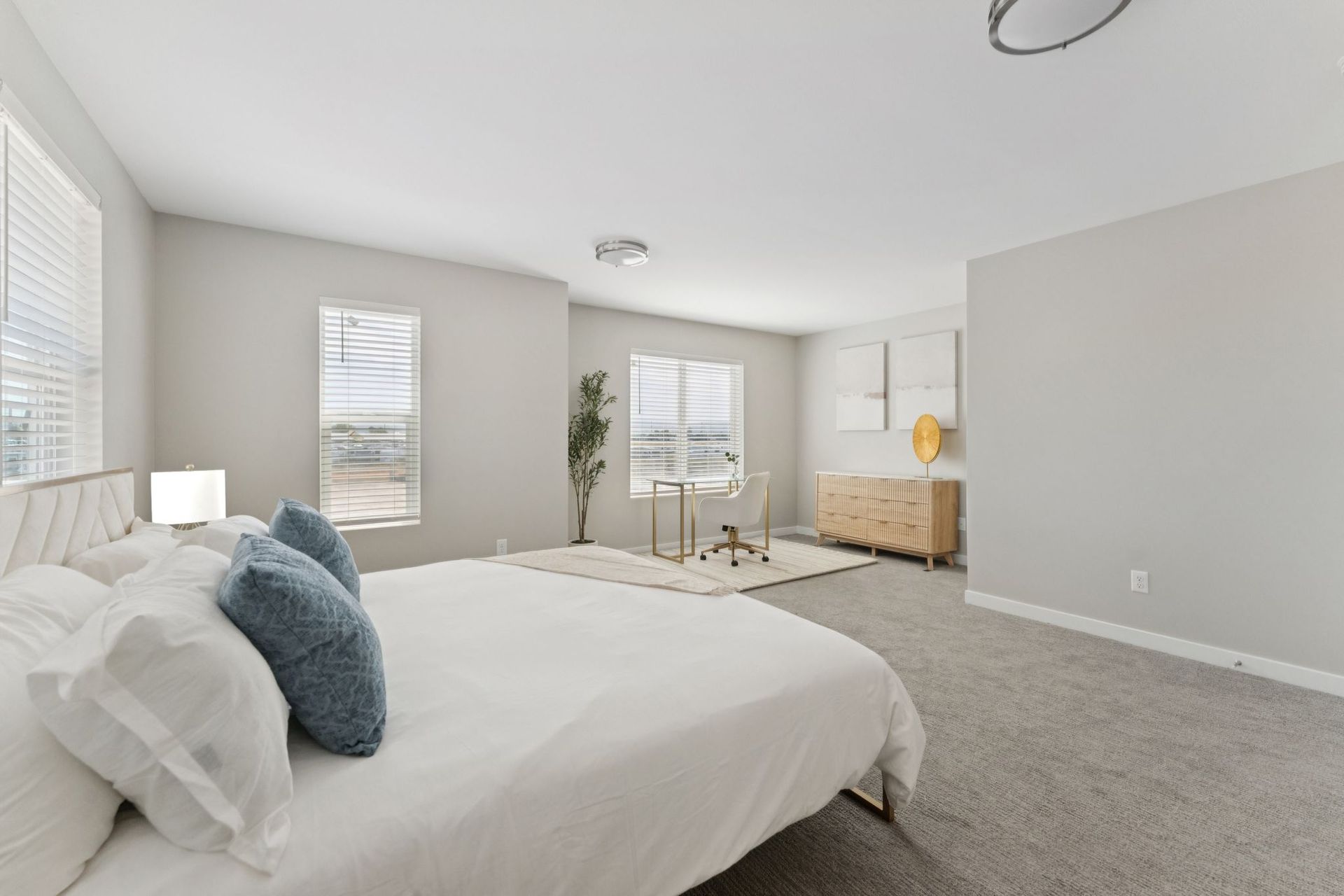 Spacious modern bedroom with a large bed, windows, and a desk area.