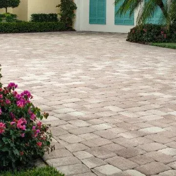 an appian stone driveway with flowers on the side of it in front of a house .