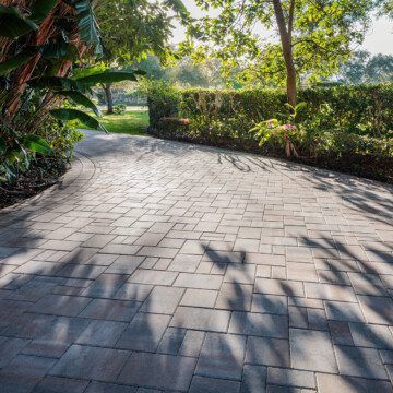 a Catalina grana driveway leading to a garden with trees and bushes .