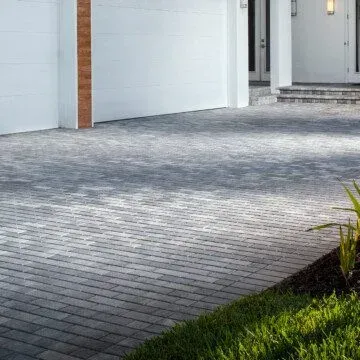 a driveway made with holland stone brick pavers leading to a white garage door.