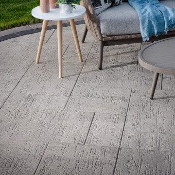 a patio with a chair , table and two tables on it .