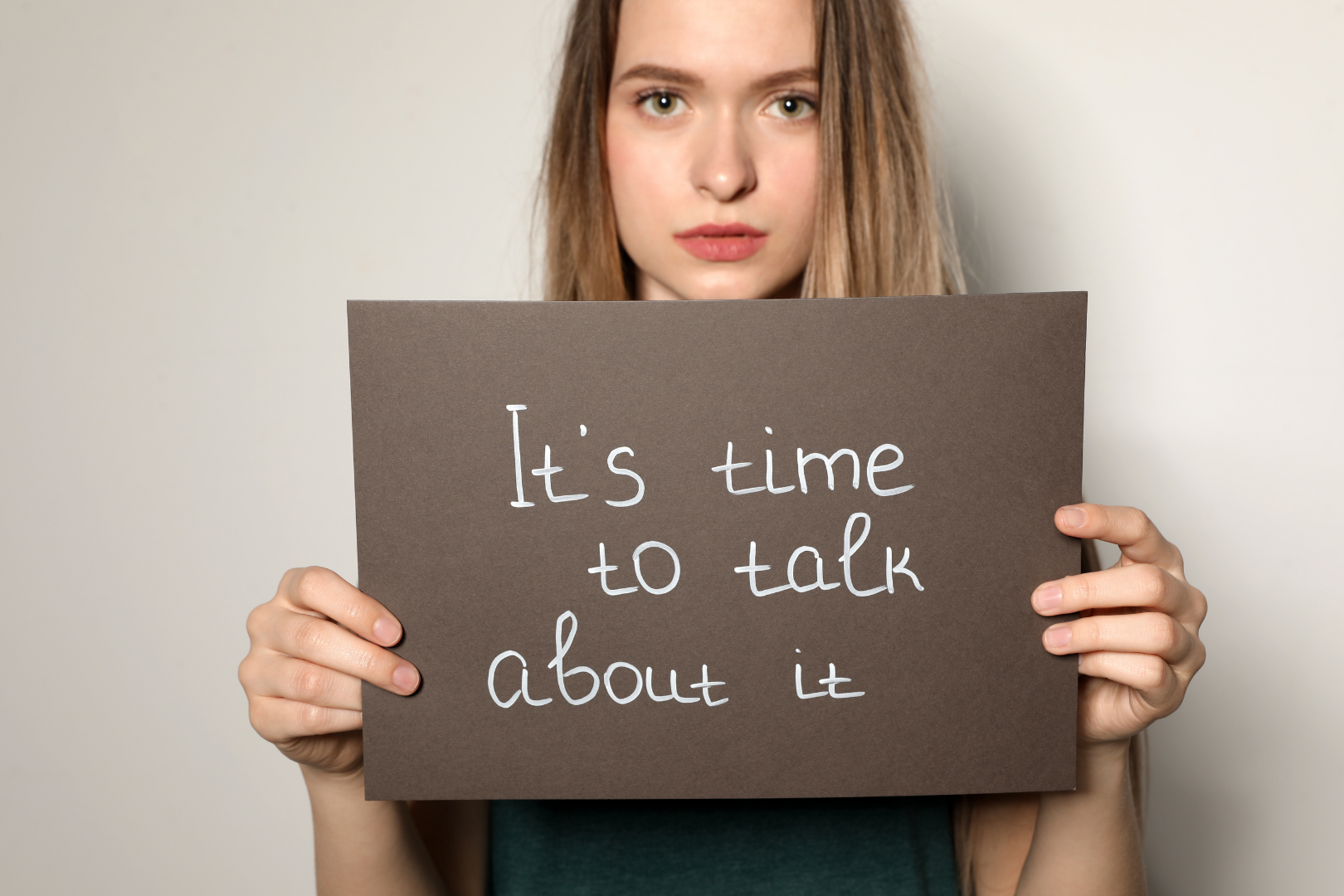 Person holding a sign that says, “It’s time to talk about it.”