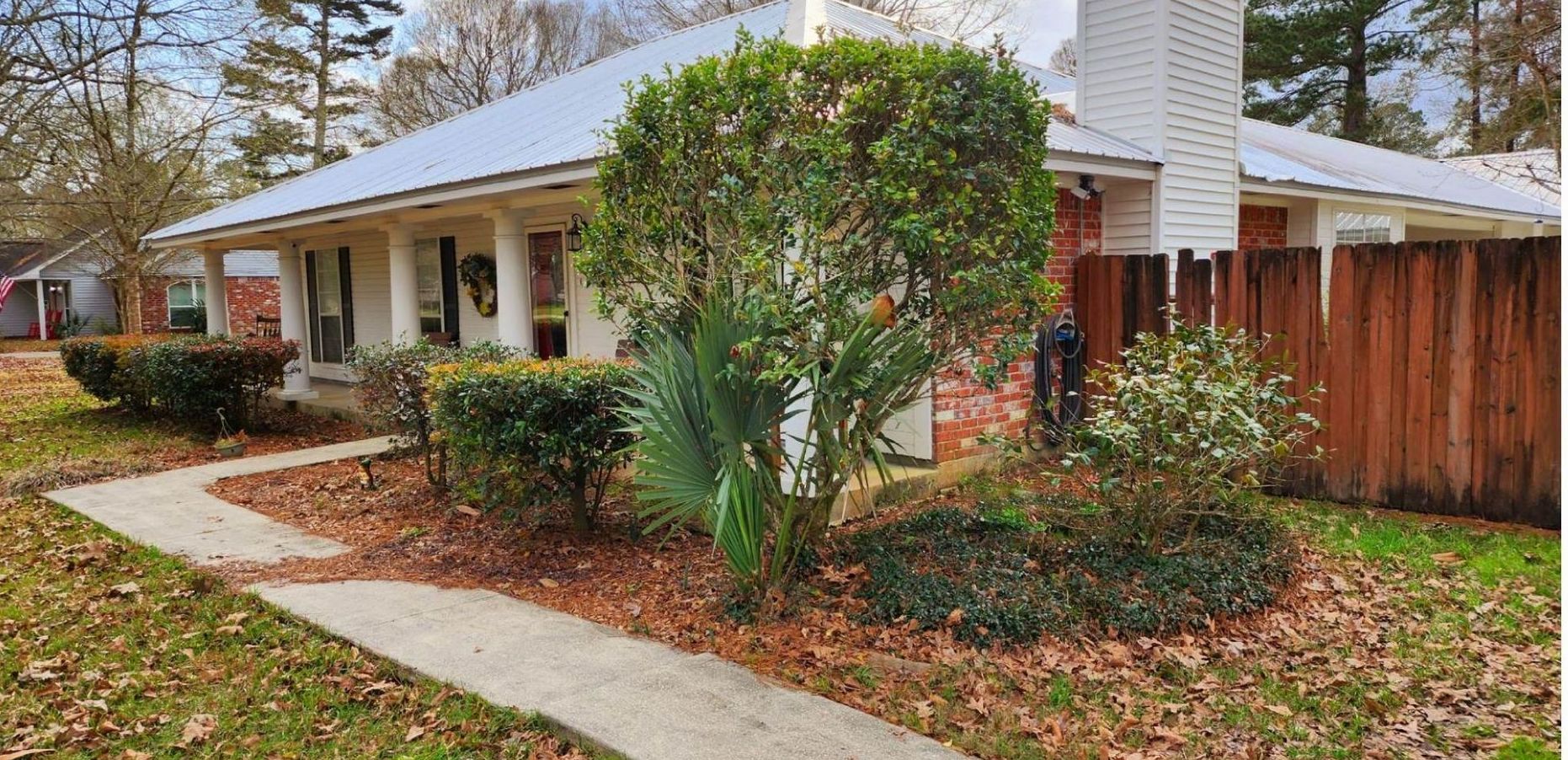 A house with a wooden fence and a walkway in front of it.