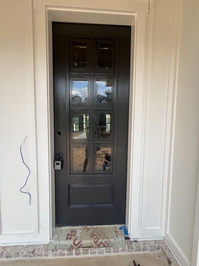 Dark gray front door with glass panels framed in white trim.