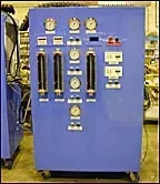 Blue industrial control panel with gauges, switches, and meters on a wheeled cabinet