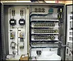 Open electrical control panel with switches, relays, and wiring inside a metal cabinet