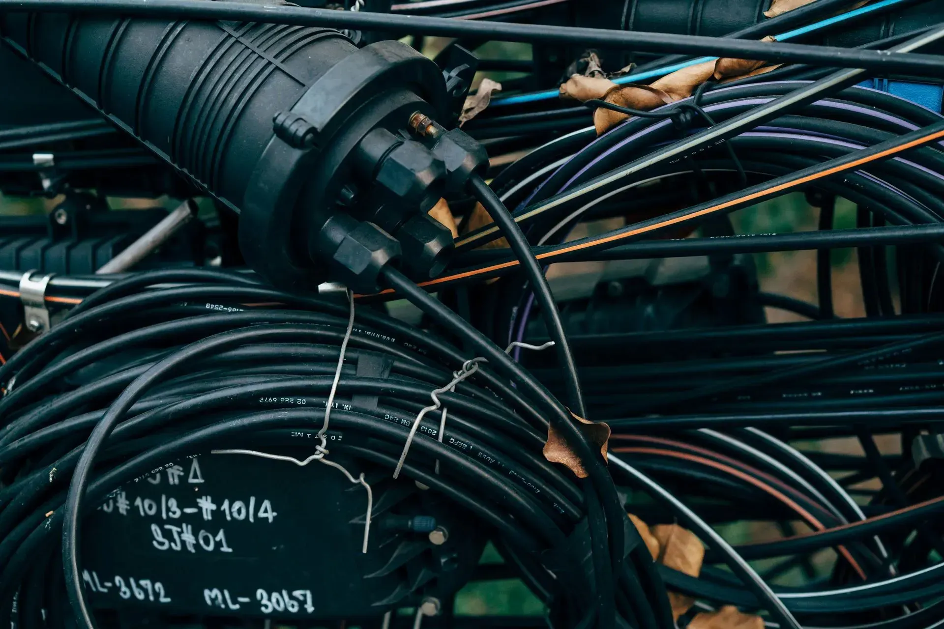 Coiled black cables and wires tangled around a large industrial spool, with handwritten markings visible.