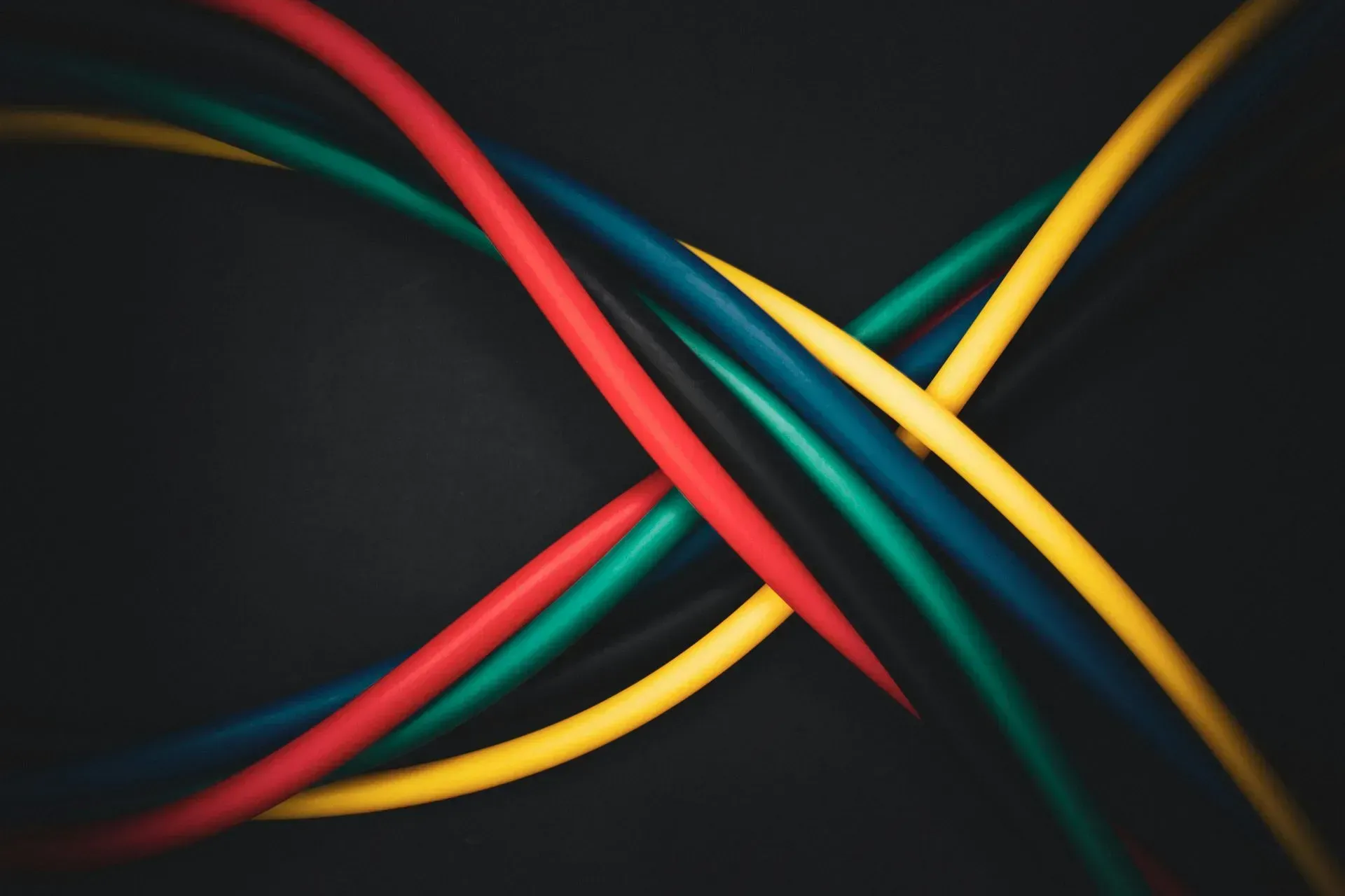 Abstract intertwined red, yellow, and teal ribbons on a dark background.