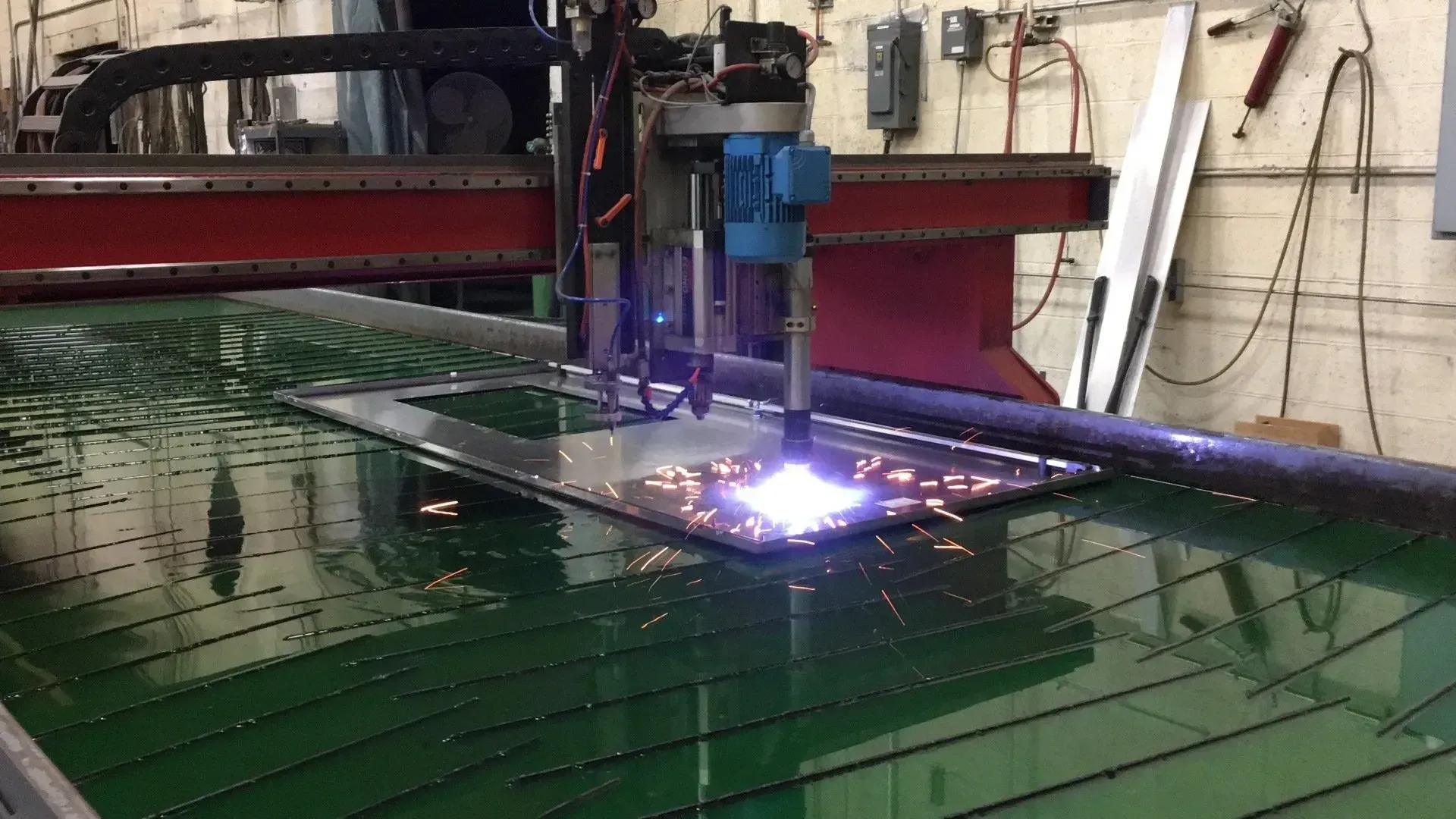 Industrial CNC plasma cutter cutting a metal sheet with bright sparks in a workshop