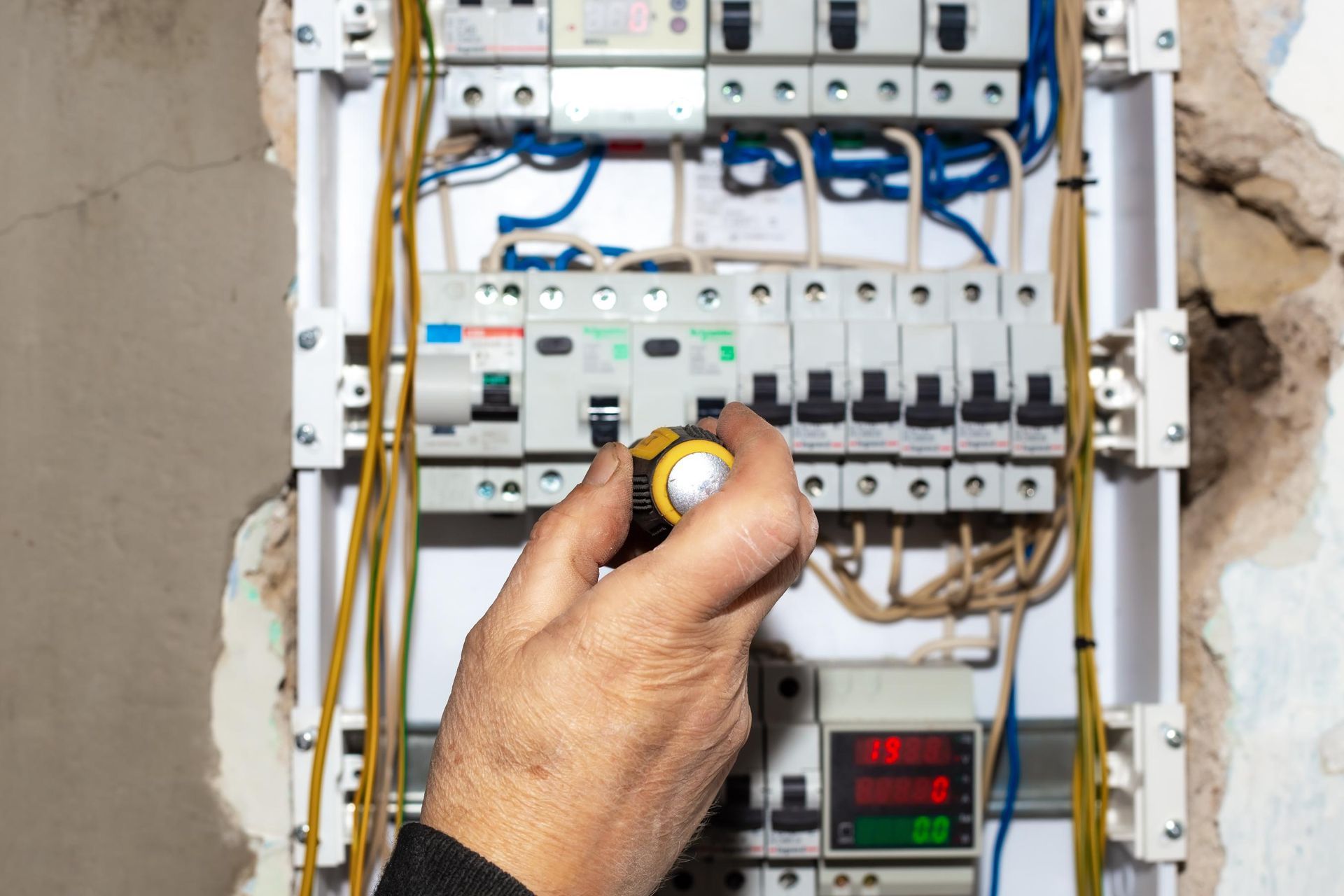 Hand adjusting a breaker switch in an electrical panel with exposed wiring
