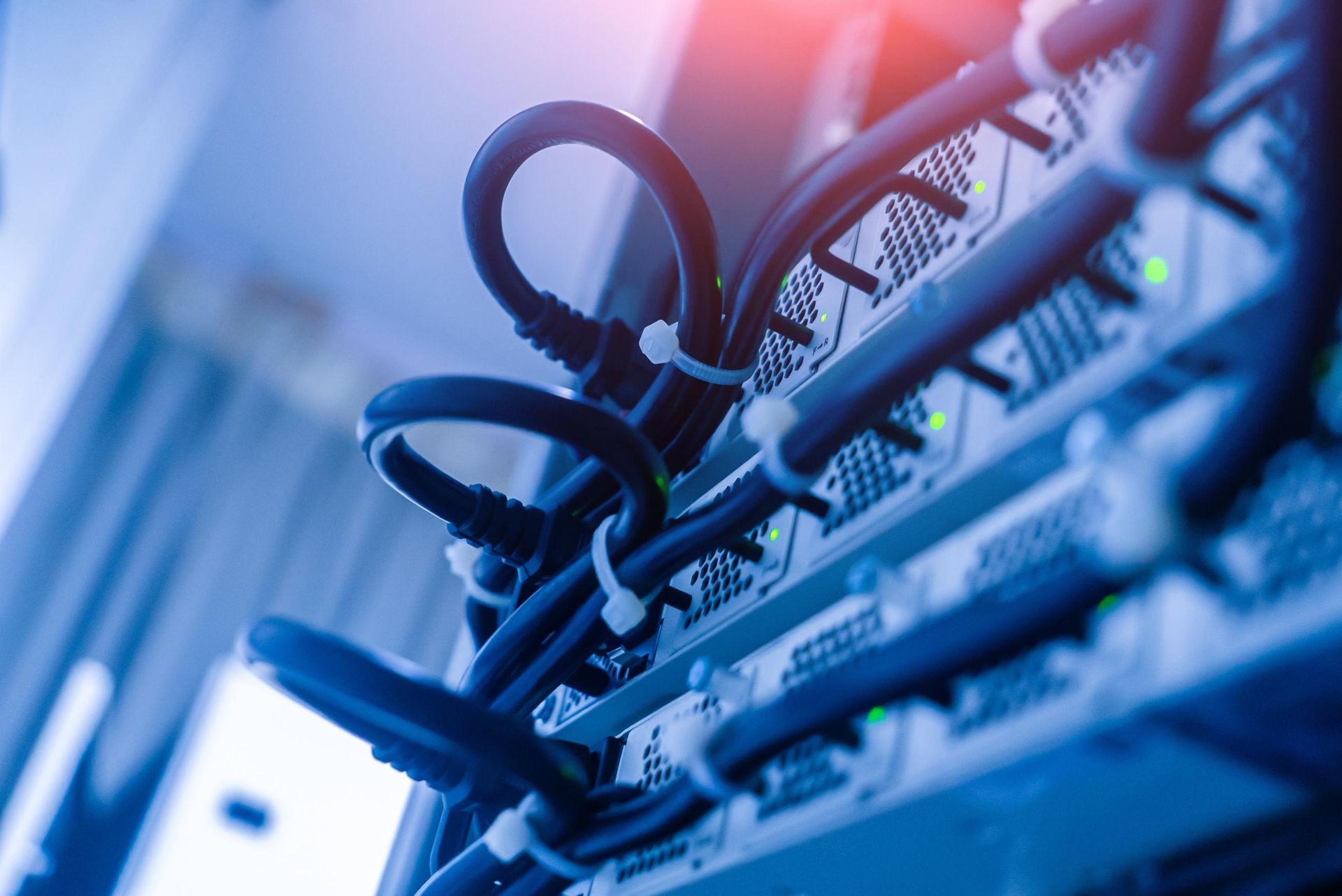 Close-up of tangled network cables and server hardware with blue lighting