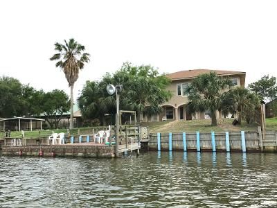 A large house is sitting on the shore of a body of water.