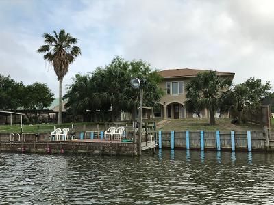 A large house is sitting on top of a hill next to a body of water.