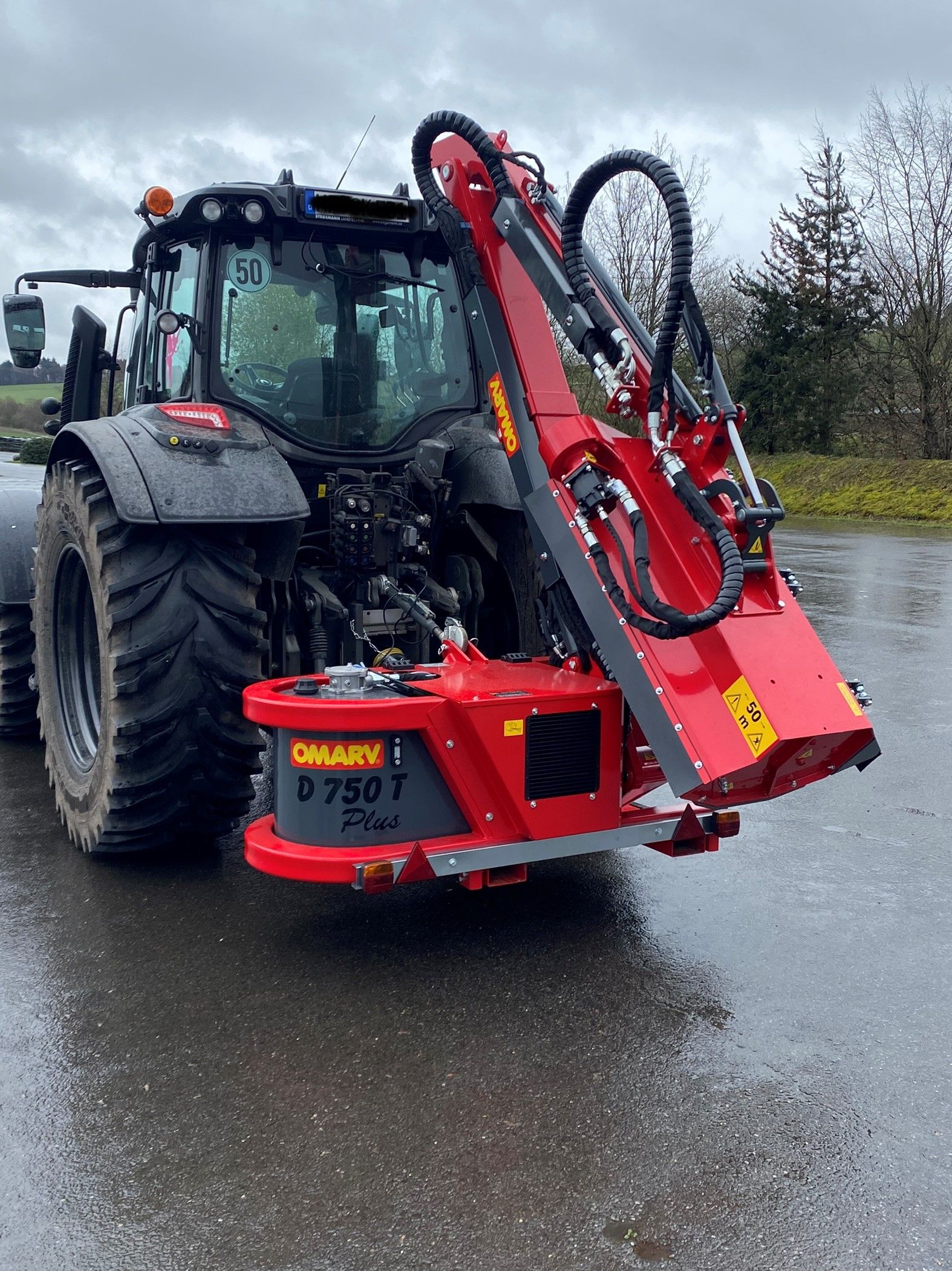 Ein rot-schwarzer Traktor steht am Straßenrand.