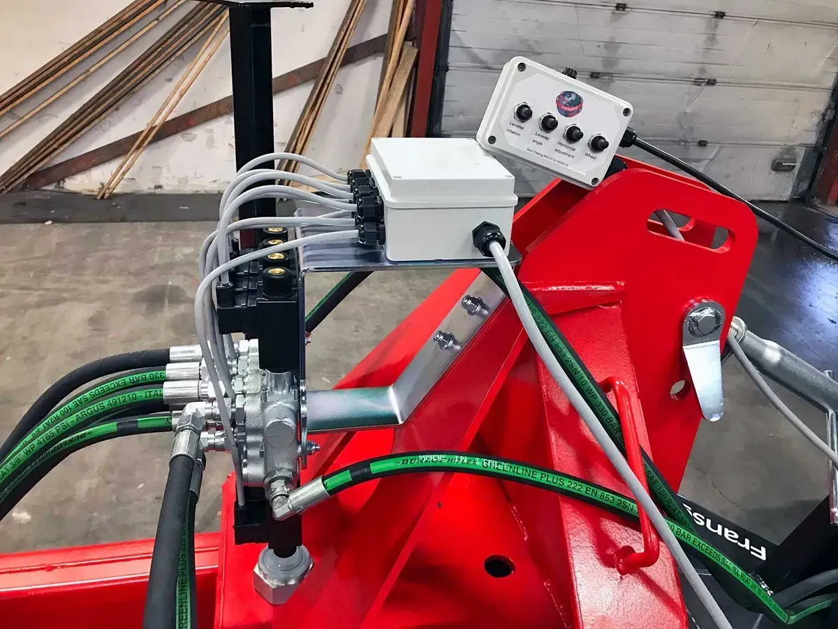 Eine rote Maschine mit Hydraulikschläuchen und einem Steuerkasten