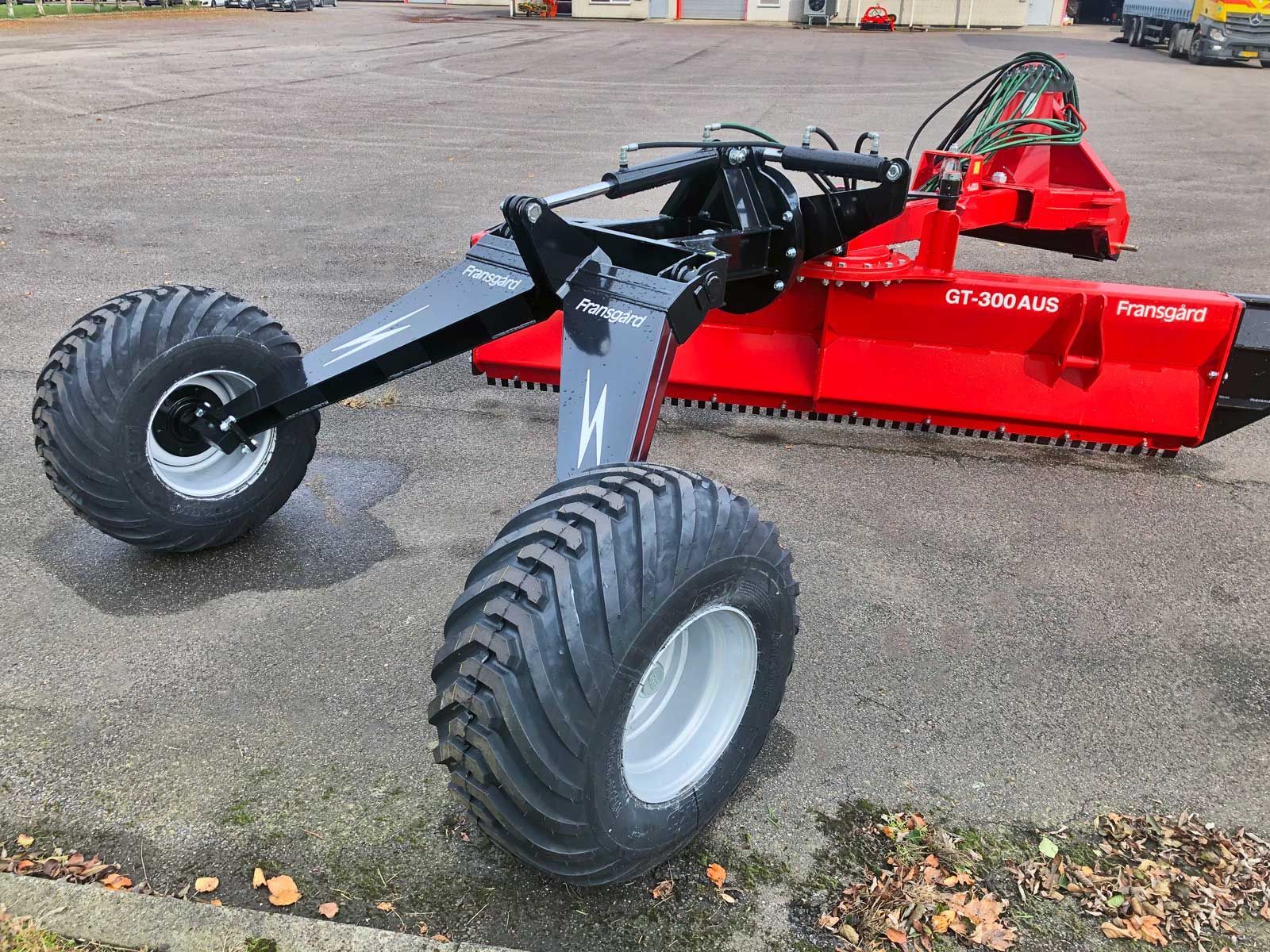 Ein rot-schwarzer Traktor steht am Straßenrand.