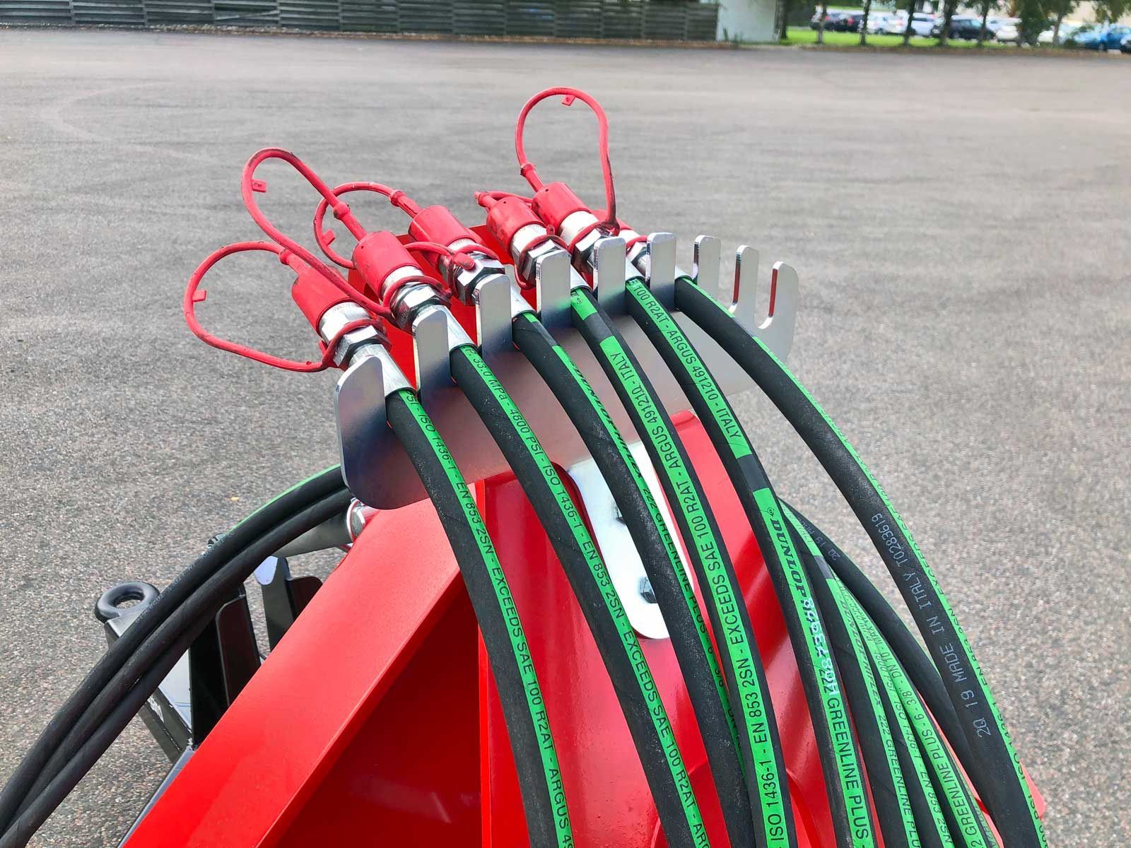 Ein Bündel Hydraulikschläuche ist an einem roten Objekt befestigt