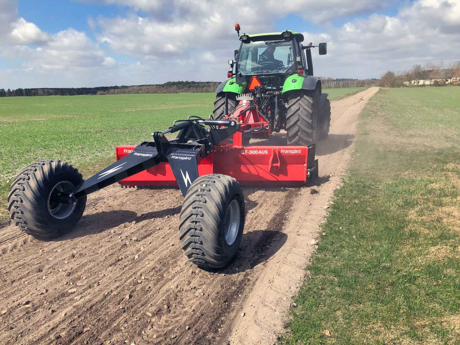 Ein Traktor pflügt ein Feld auf einer unbefestigten Straße