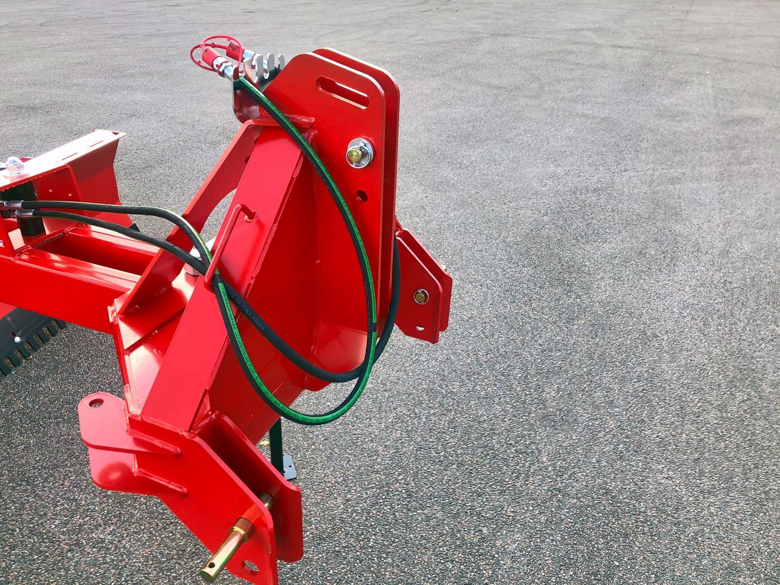 Ein roter Traktor mit einem daran befestigten grünen Schlauch