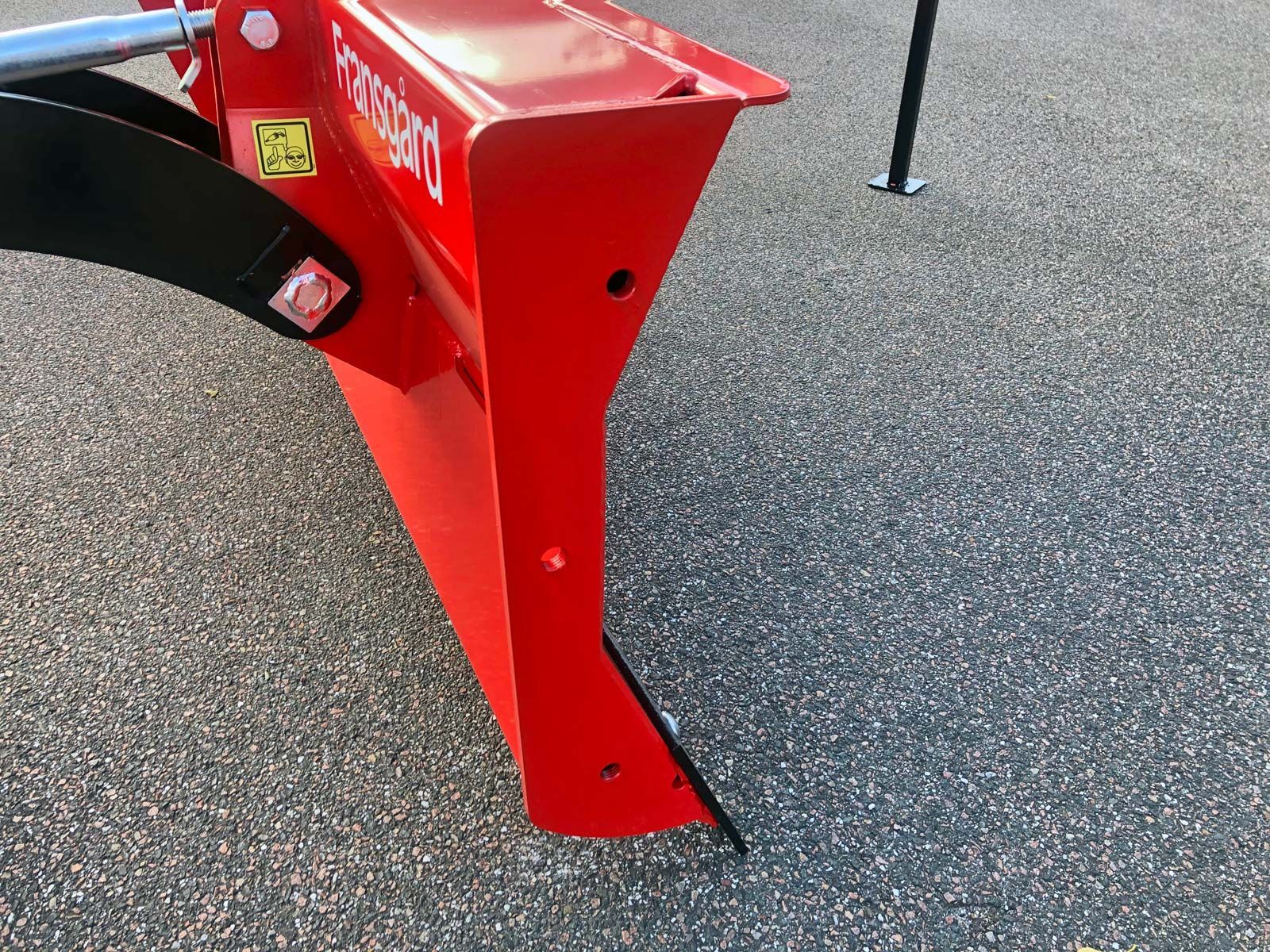 Ein roter Traktor steht auf einer Schotterstraße