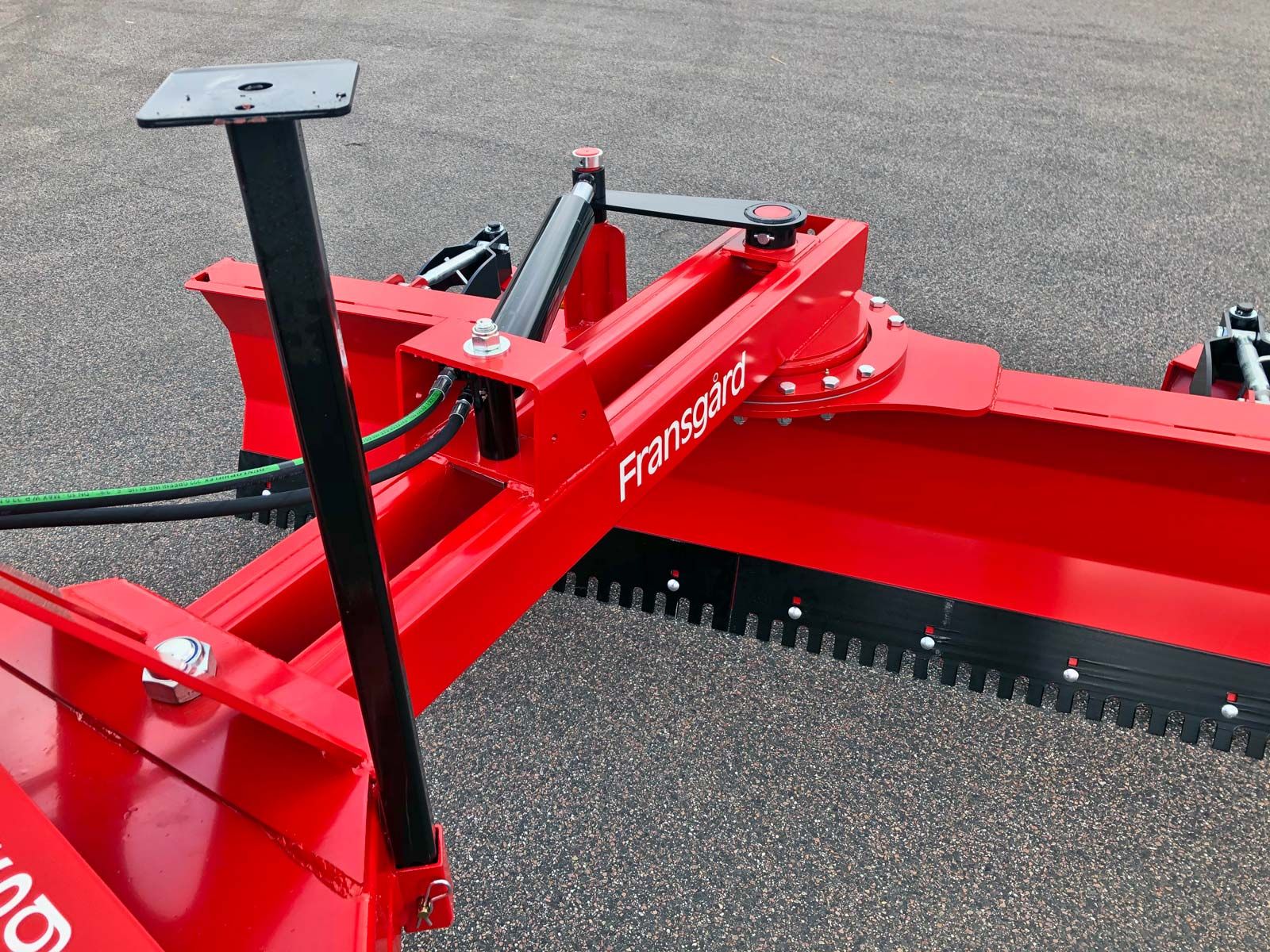 Auf dem Boden steht ein roter Traktor mit einer schwarzen Klinge.