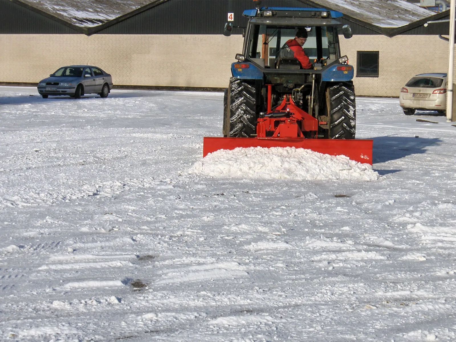 Ein Traktor räumt Schnee auf einem Parkplatz