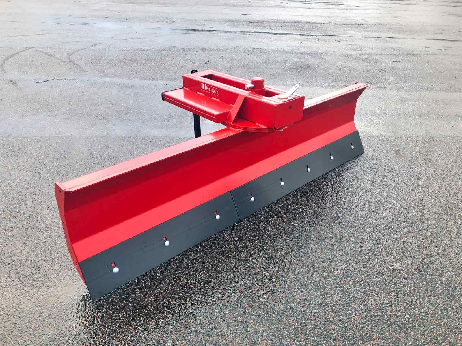Auf dem Boden steht ein rot-schwarzer Schneepflug.