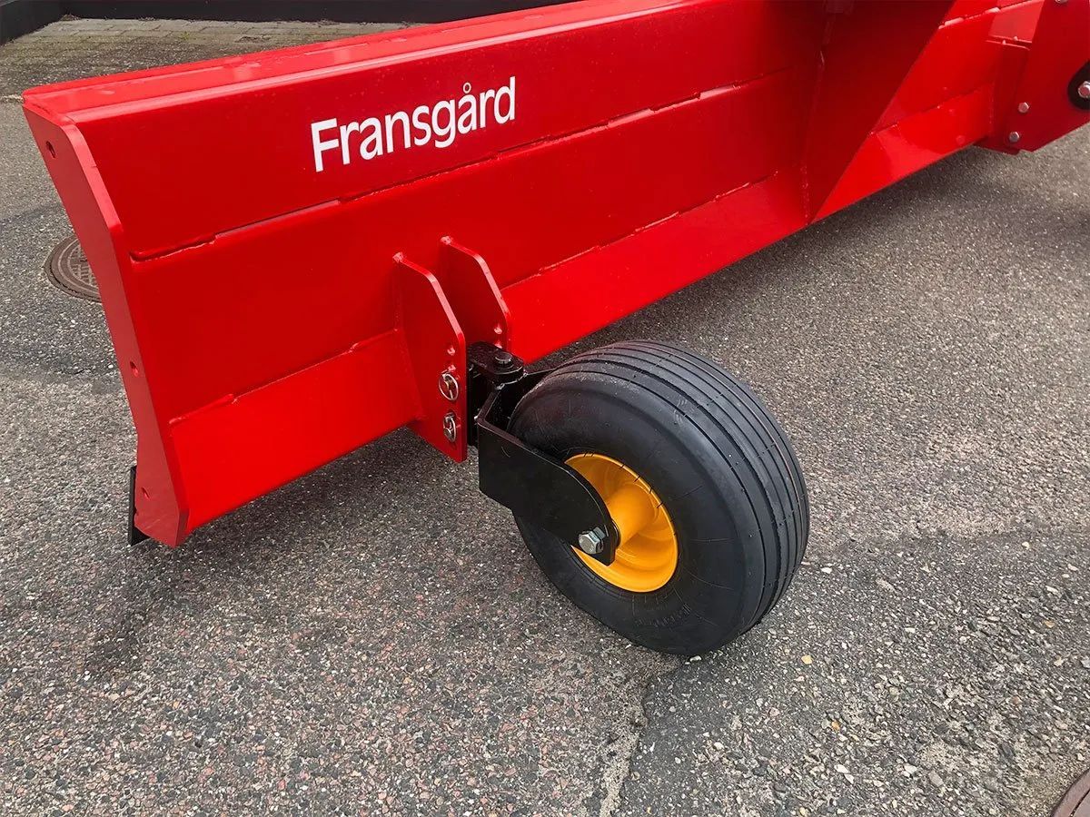 Auf dem Boden liegt ein roter Pflug mit einem gelben Rad.