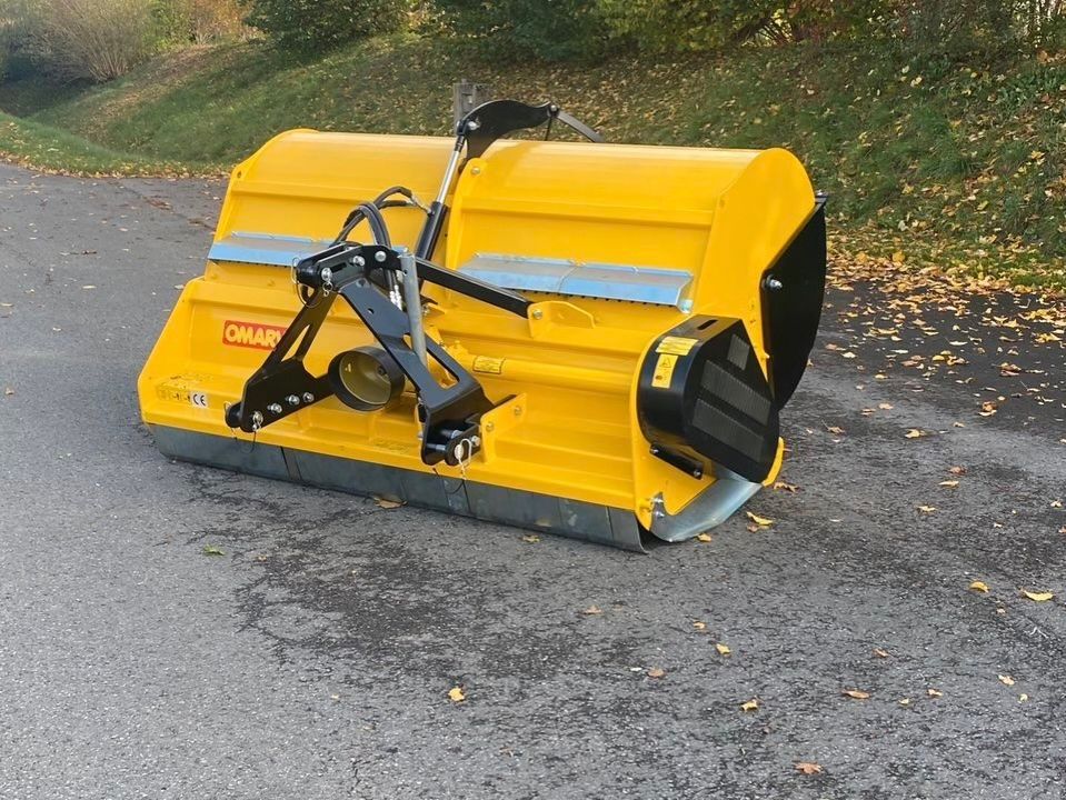 Ein rot-grauer Rasenmäher steht auf dem Boden.