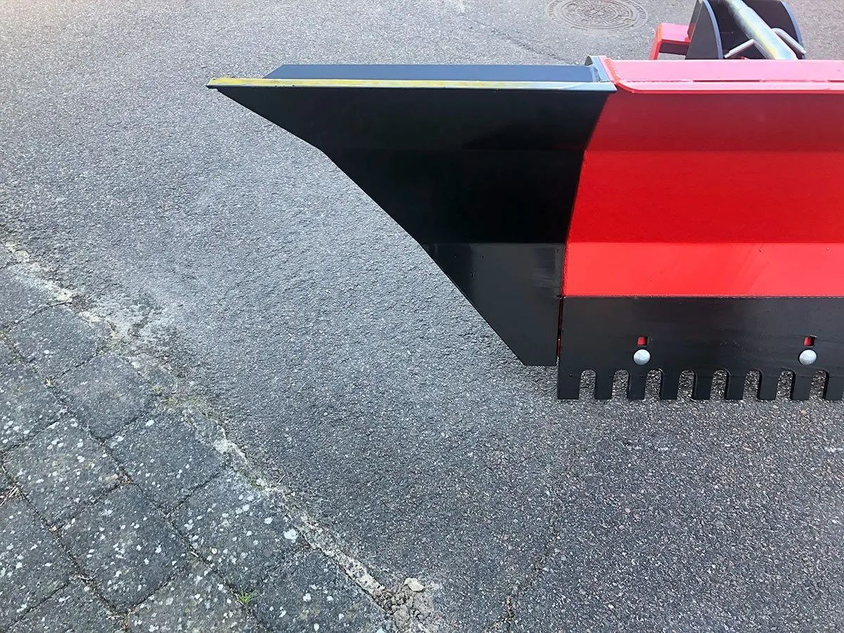 Ein rot-schwarzer Traktor steht am Straßenrand.