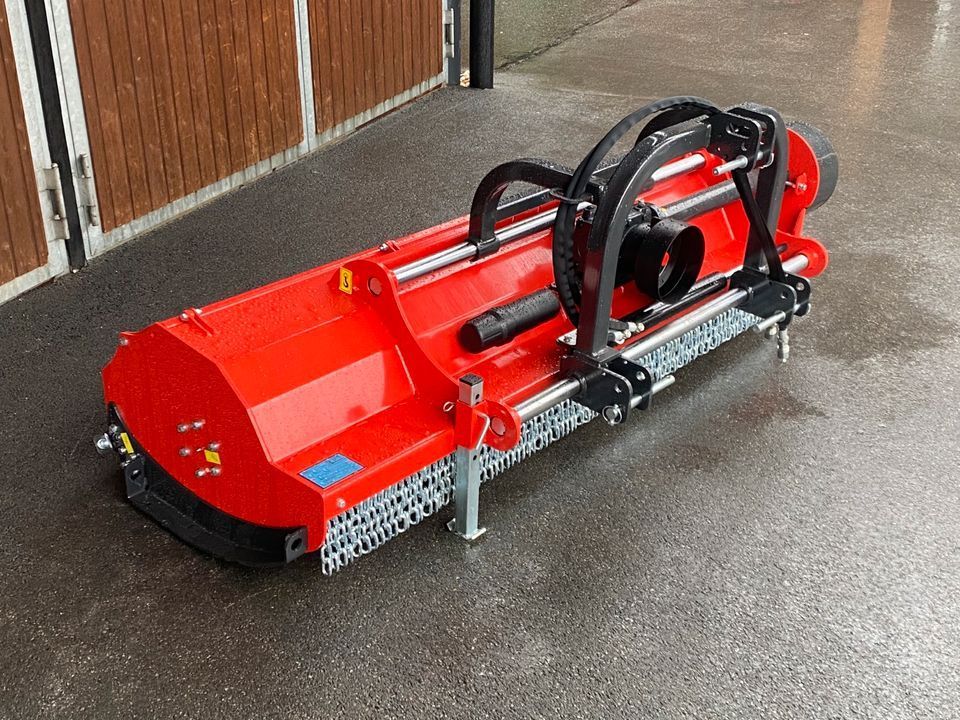 Eine rote Maschine steht auf dem Boden vor einer Holztür.