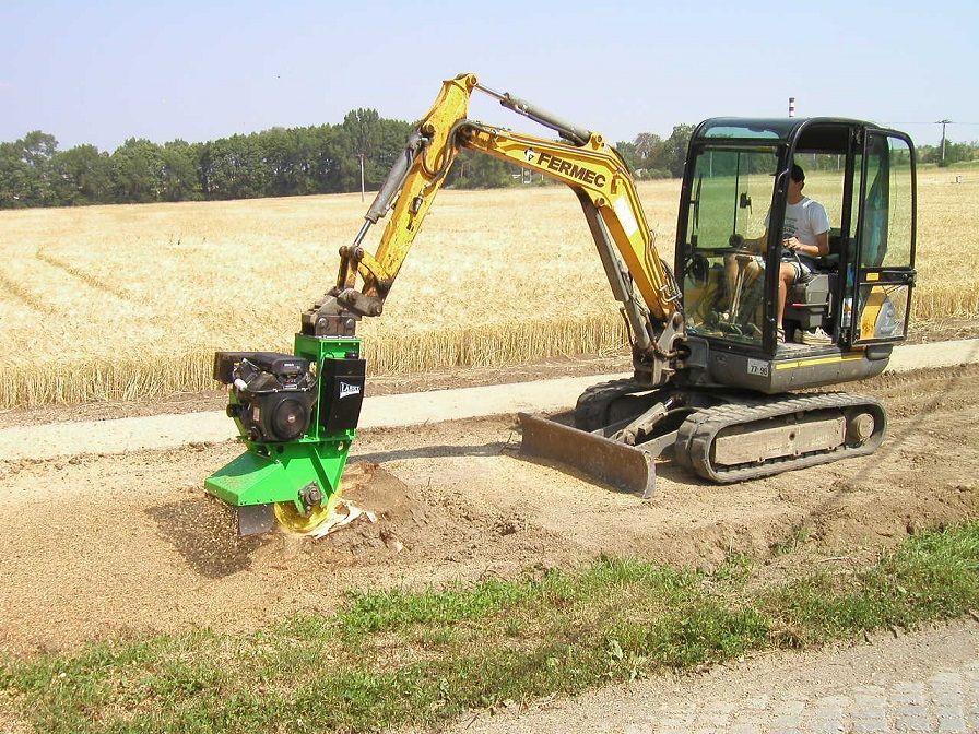 Ein Mann fährt einen gelb-grünen Bagger auf einer unbefestigten Straße