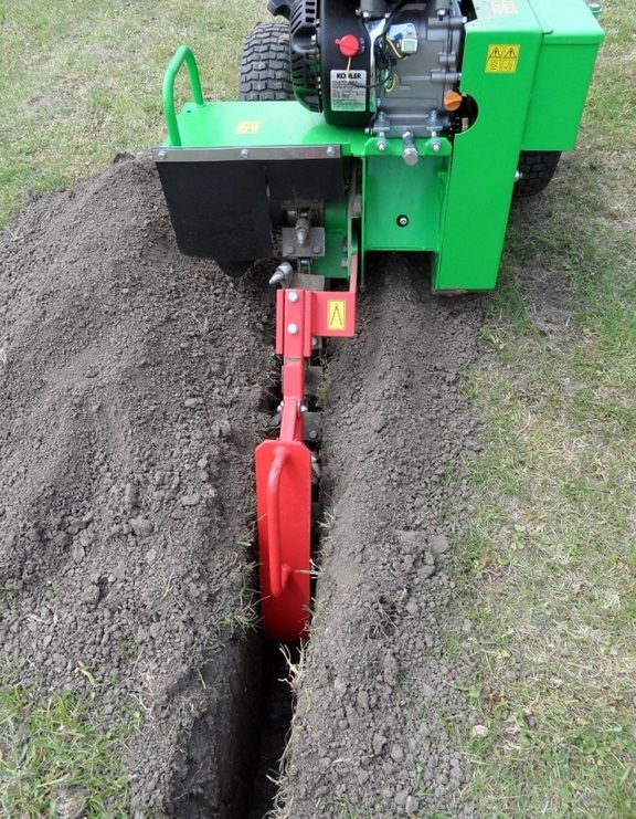 Eine grün-rote Maschine gräbt ein Loch in den Boden