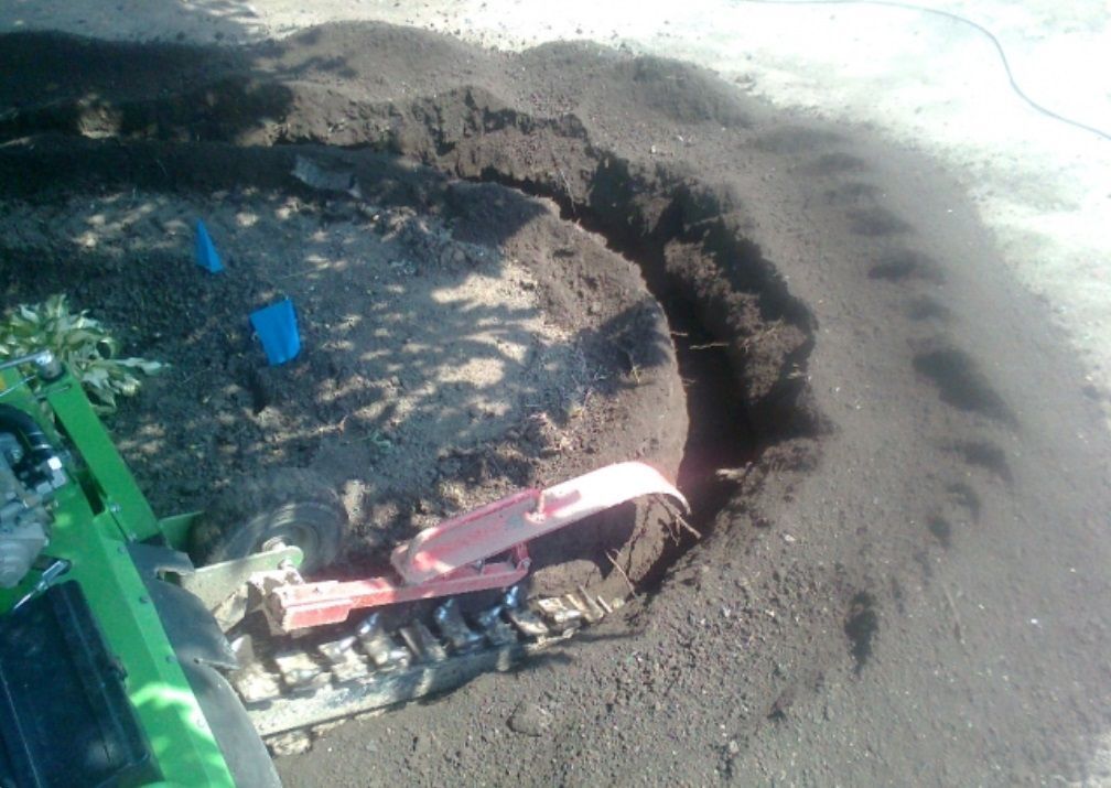 Ein grüner Traktor gräbt ein Loch in den Boden