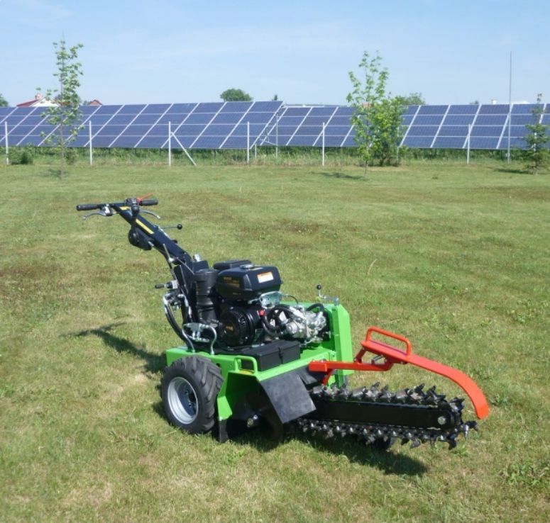 Ein grüner Traktor steht auf einer Wiese mit Sonnenkollektoren im Hintergrund