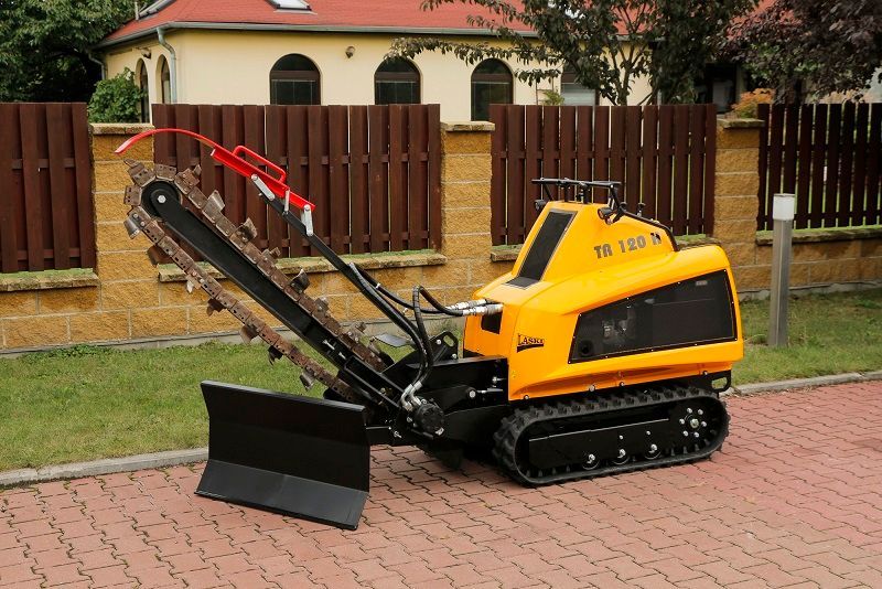 Ein kleiner gelber Traktor mit einer daran befestigten Kettensäge steht am Straßenrand.