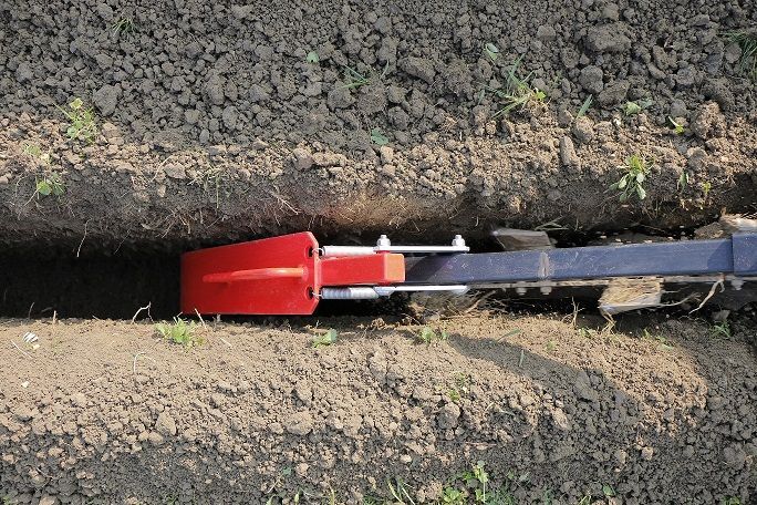 Eine rote Schaufel ragt aus einem Loch im Boden