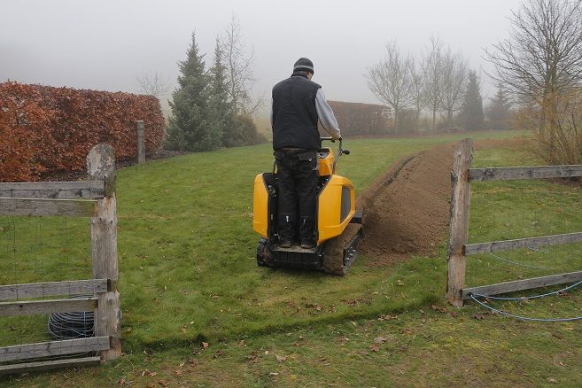 Ein Mann fährt einen gelben Traktor durch eine Wiese.