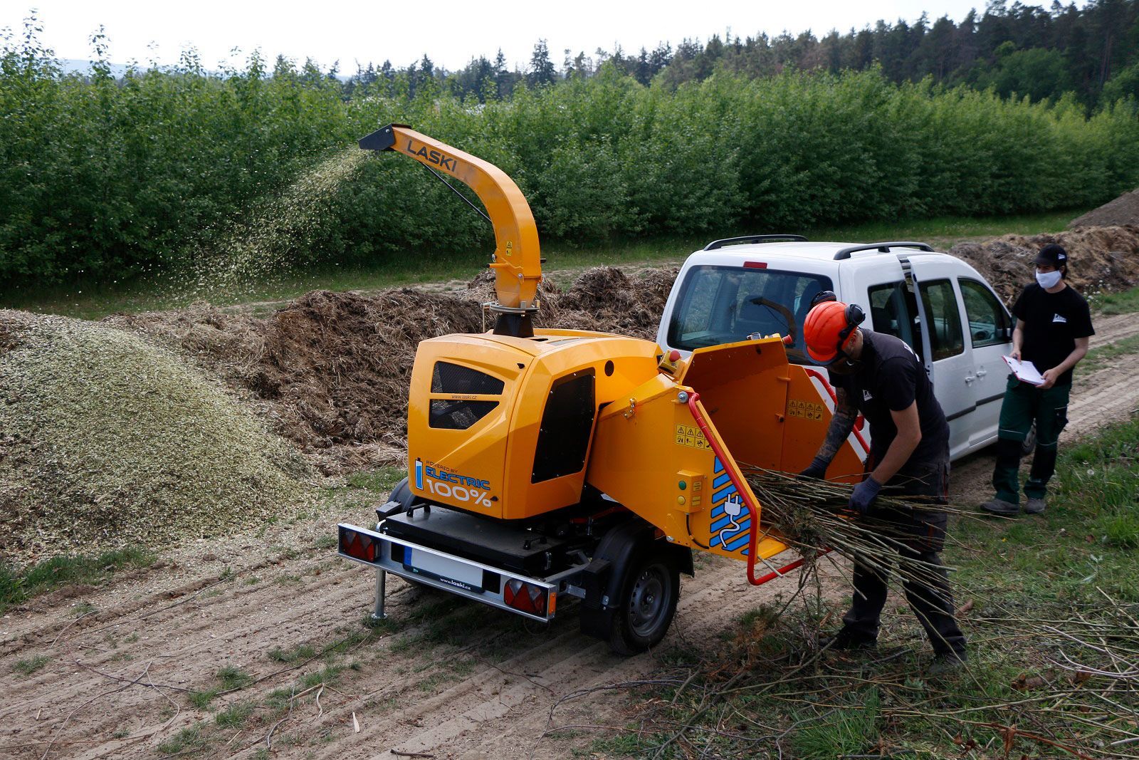 Ein Mann steht neben einer Maschine, die Holz schneidet.