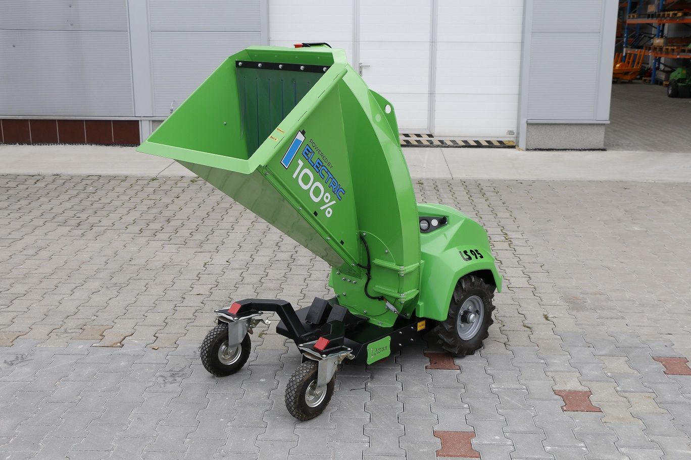 Eine grüne Maschine mit Rädern steht auf einem gepflasterten Gehweg.